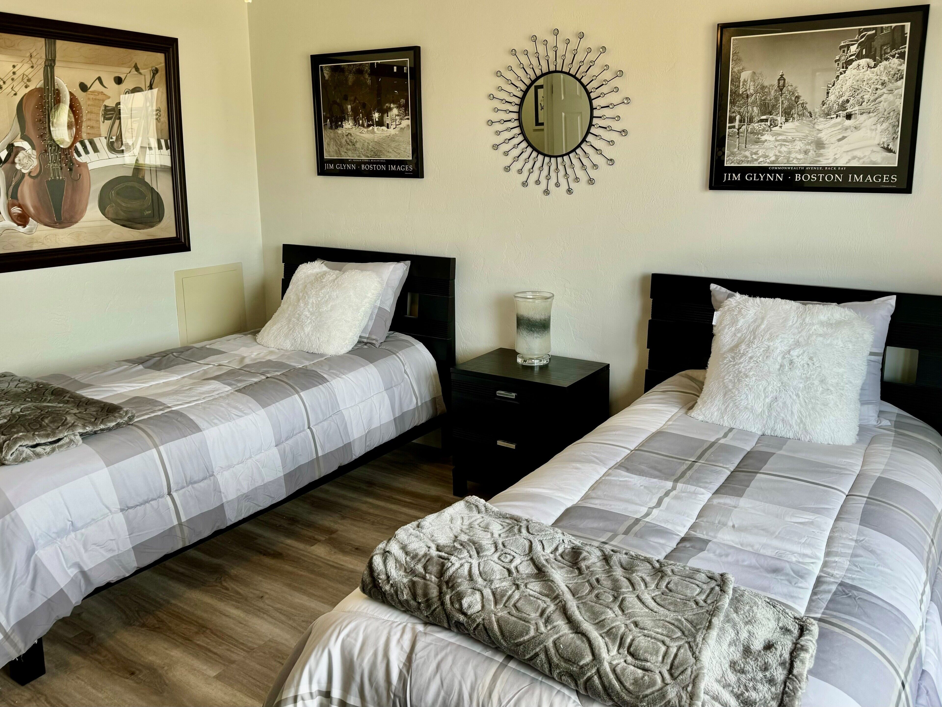 A hotel room with two beds, a nightstand, and a wall clock.