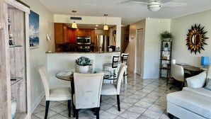 A modern kitchen with wooden cabinets, stainless steel appliances, and a dining area with a round table and four chairs. - Modern St Augustine Beach Condo with Pool and Private Garage, Steps to Ocean. (St. Augustine)