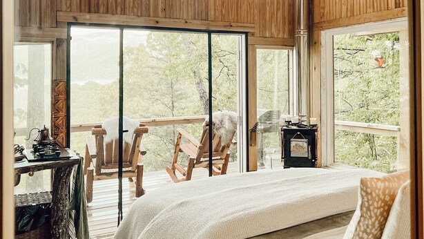 Ein gemütliches Schlafzimmer mit einem großen Bett, Holzwänden und Blick ins Freie.