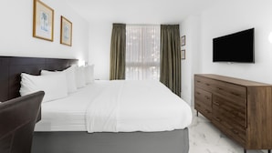 Une chambre d’hôtel avec un lit, une commode en bois, un téléviseur à écran plat et deux tableaux encadrés au mur.