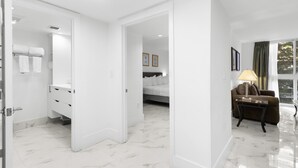 A hotel room with a bathroom, a bed, a sofa, and a view of trees through the window. - Tranquil Condo in Coconut Grove w/ Pool (Miami)