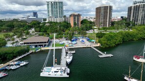 A marina with boats docked, a building with a flat roof, and surrounding greenery.