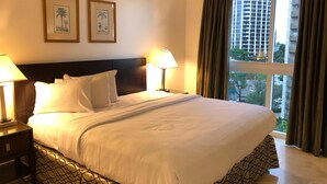 A hotel room with a large bed, two bedside lamps, a headboard, and two framed pictures on the wall.