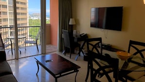 A hotel room with a balcony, a TV, a desk, and a sofa.