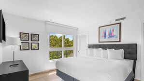 A bedroom with a bed, a TV, a window, and a painting on the wall. - Resort Style Condo, onsite Restaurant & Bar (Miami)