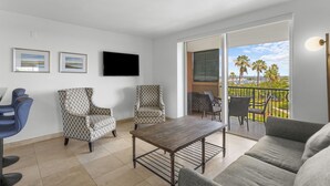 A living room with a sofa, armchairs, a coffee table, a TV, and a balcony with outdoor furniture. - Resort Style Condo, onsite Restaurant & Bar (Miami)