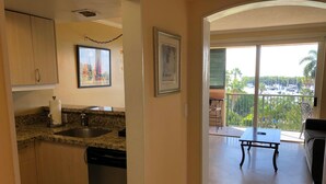 A kitchen with granite countertops, a dishwasher, and a dining area with a table and chairs. - Family Retreat, 2 Bedroom Condo, Pool Access (Miami)