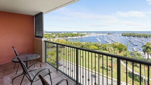 A balcony with a table and chairs, overlooking a marina with boats and greenery. - Luxury 2/2 Condo with balcony in Coconut Grove (Miami)