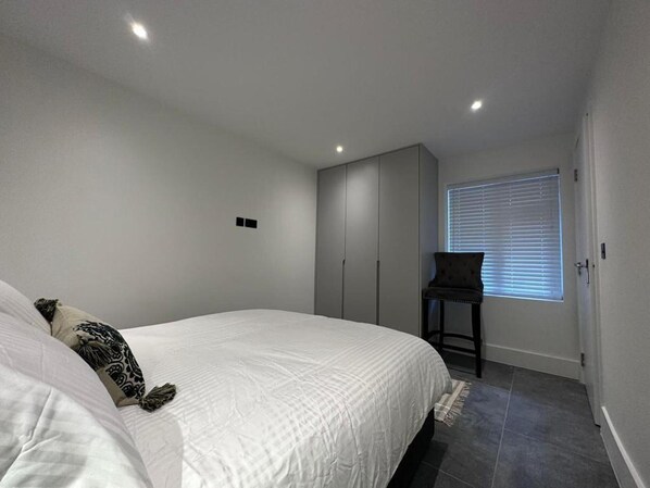 A bedroom with a bed, a wardrobe, a chair, and a window with blinds. - House - Sleeps 4 & Free Parking (London)