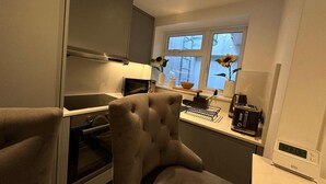 A modern kitchen with a built-in oven, microwave, and a coffee machine on the counter. - House - Sleeps 4 & Free Parking (London)