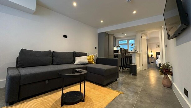 A modern living room with a grey sofa, a small black side table, and a yellow rug. - House - Sleeps 4 & Free Parking (London)