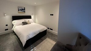 A modern bedroom with a large bed, a headboard, a painting on the wall, and recessed ceiling lights. - House - Sleeps 4 & Free Parking (London)