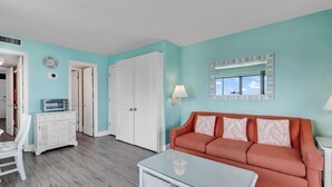 Un salon avec un mur de couleur turquoise, un canapé rouge, une table basse blanche et un meuble blanc.