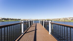 A wooden boardwalk leading to a body of water, flanked by metal railings.