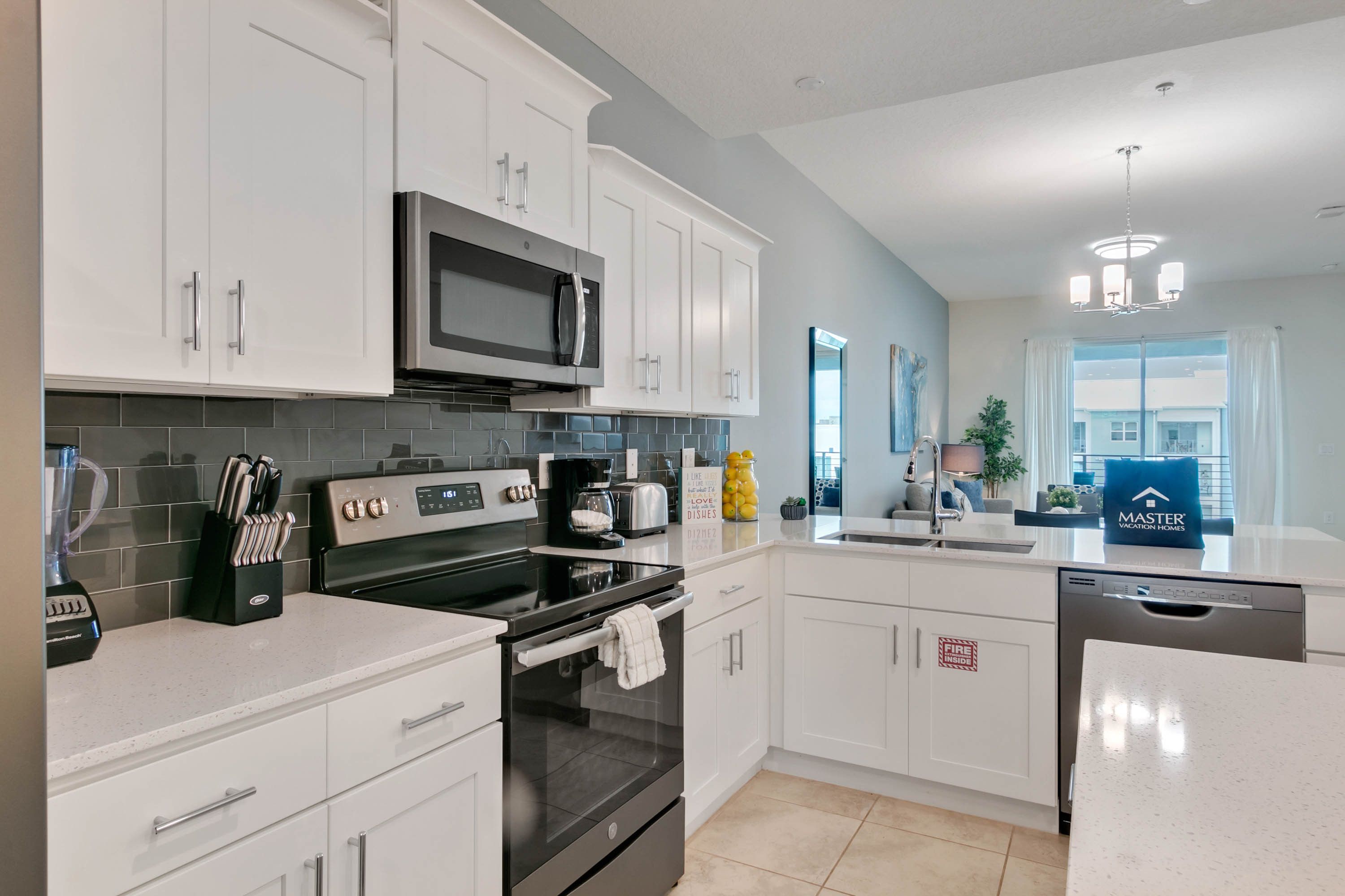 A modern kitchen with white cabinetry, a built-in microwave, a stove, and a coffee maker.