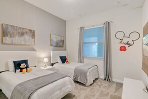 A hotel room with two beds, a window with curtains, a Mickey Mouse wall decal, and abstract art on the walls. - Last Minute Disney Getaway! Luxury Condo with Private Balcony. Book Now! #65757 (Orlando)