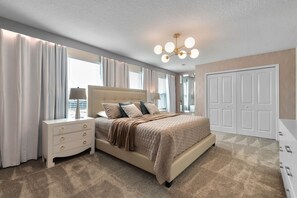 A bedroom with a large bed, a nightstand, a dresser, and a closet.