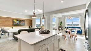 A modern kitchen with a central island, pendant lighting, and a dining area with a view. - Last Minute Disney Getaway! Luxury Condo with Private Balcony. Book Now! #65877 (Orlando)
