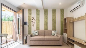 Un salón moderno con un sofá beige, una estantería de madera y un ventanal corredero que da a un balcón.