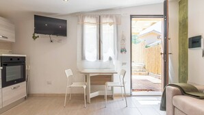 Cocina compacta con televisor, comedor para dos personas y vistas al exterior.