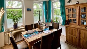 Un coin repas comprenant une table en bois, des chaises et un buffet aux portes vitrées.