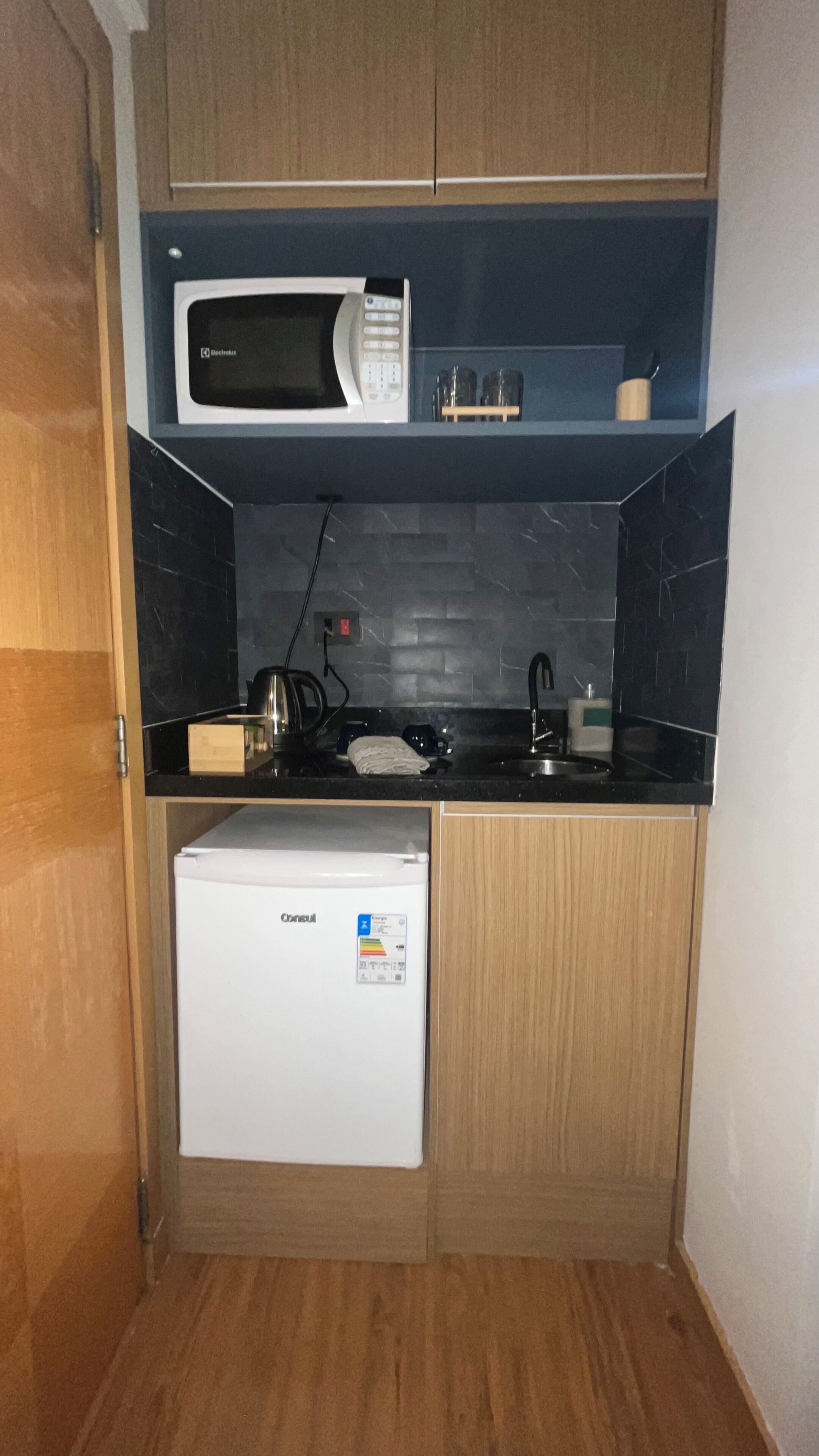 A compact kitchen with a microwave, a small refrigerator, and a sink.