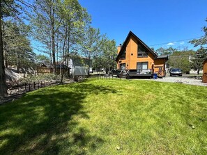 A modern two-story house with a sloped roof, a visible chimney, and a well-maintained lawn. - Pet Friendly, Pocono Chalet, Lake Community (Tobyhanna)