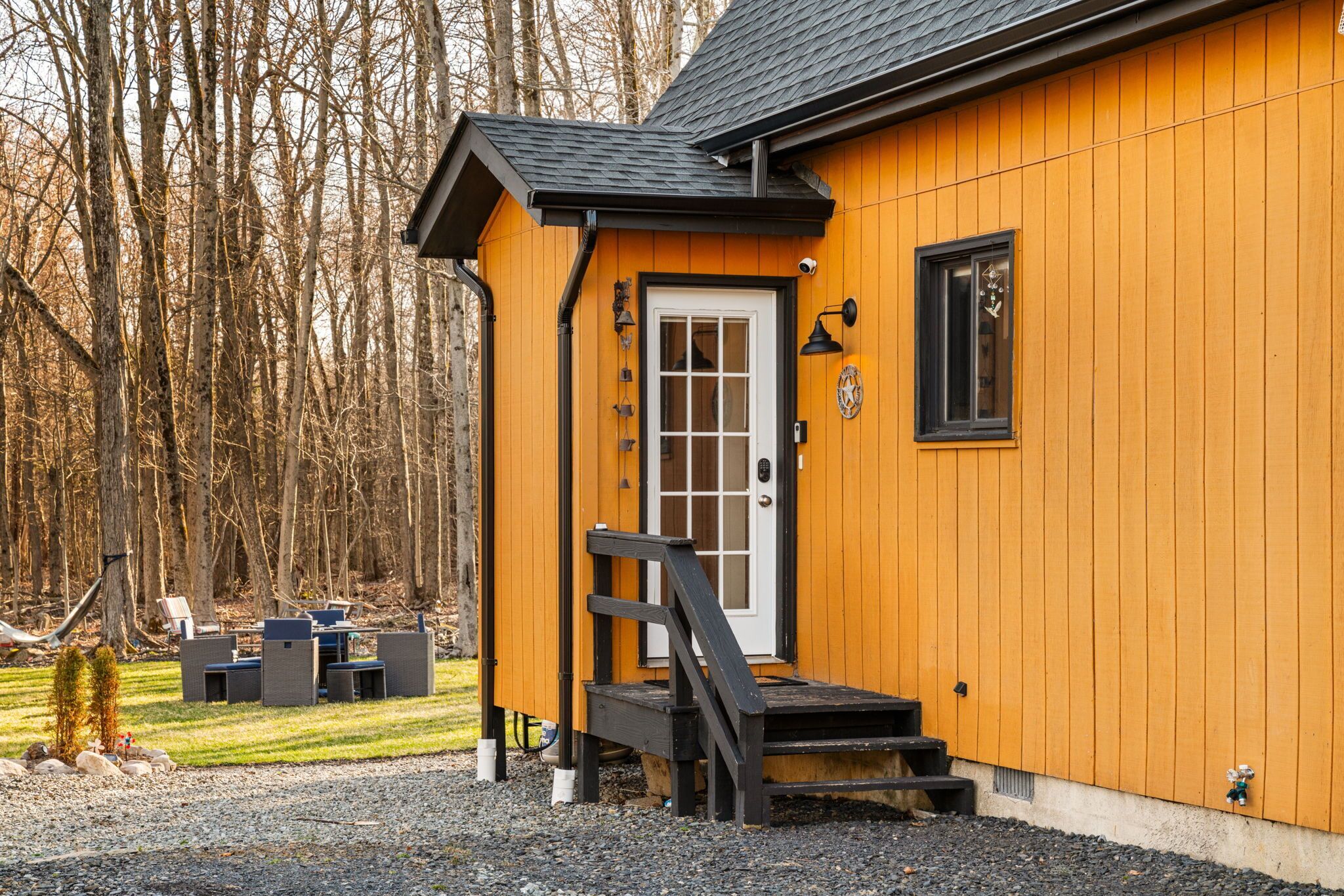Une cabane en bois avec une porte blanche, un petit porche et un banc noir.