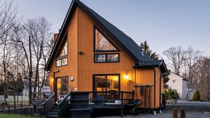 Ein zweistöckiges Holzhaus mit einer großen Veranda, einer Treppe zum Eingang und einer Garage.