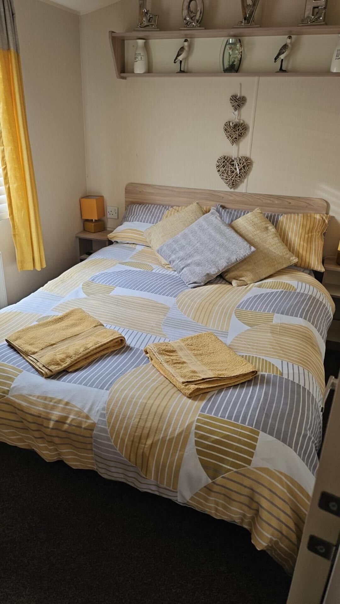 A neatly made bed with striped bedding, a bedside lamp, and decorative wall shelves.