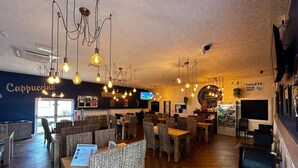 Interno di un ristorante con lampadari e un'area bar, e un segnale che indica la direzione dei servizi igienici.
