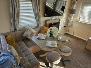A living room with a sofa, a coffee table, and a TV. - 3 Bed Caravan - Sleeps 6 - Pets - Parking - Wifi (Skegness)