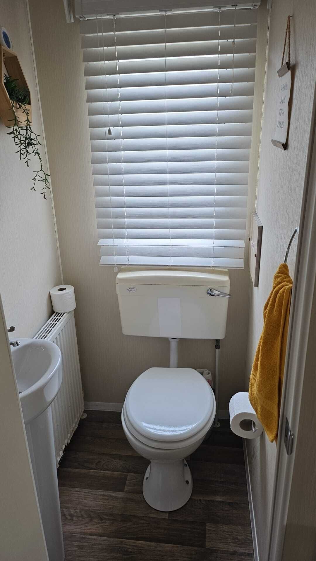 Ein kleines, kompaktes Badezimmer mit Toilette, einem Heizkörper und einem Handtuch an der Wand.