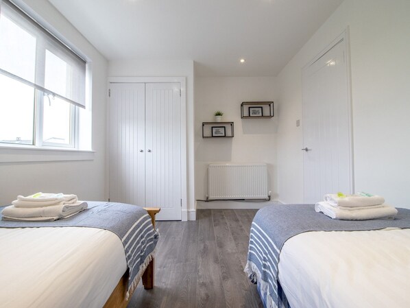 A bedroom with two beds, a radiator, a window, and a door. - Renfrew Town Centre, Easy Link to Glasgow City - Pass the Keys (Renfrew)