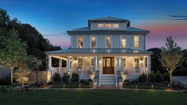A two-story house with a front porch, large windows, and a well-maintained lawn.