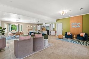 A spacious living area with a dining table, sofas, and a kitchen in the background.