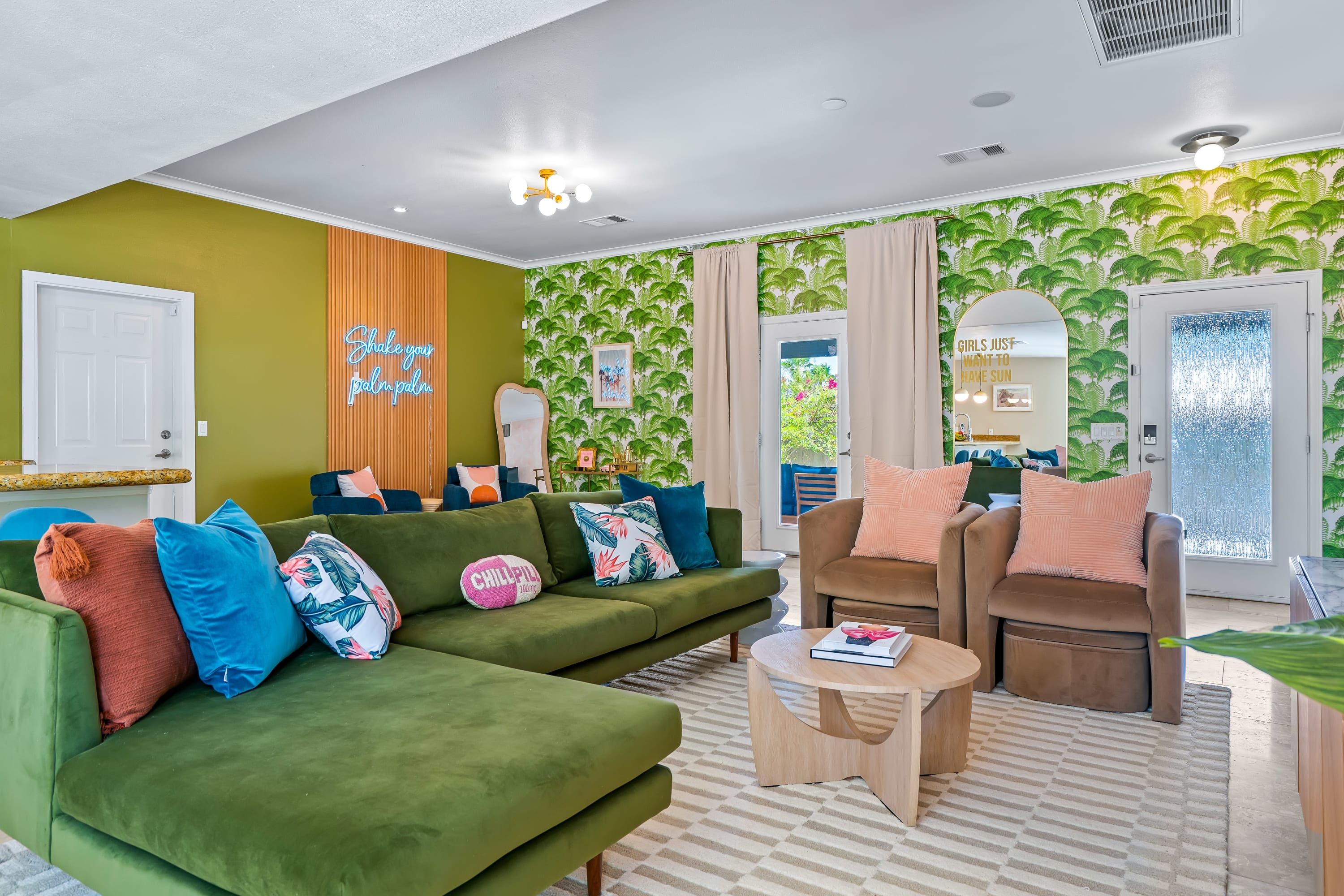 A modern living room with a green sofa, a brown armchair, and a coffee table. There are two doors, one with a mirror and the other with a frosted glass window.