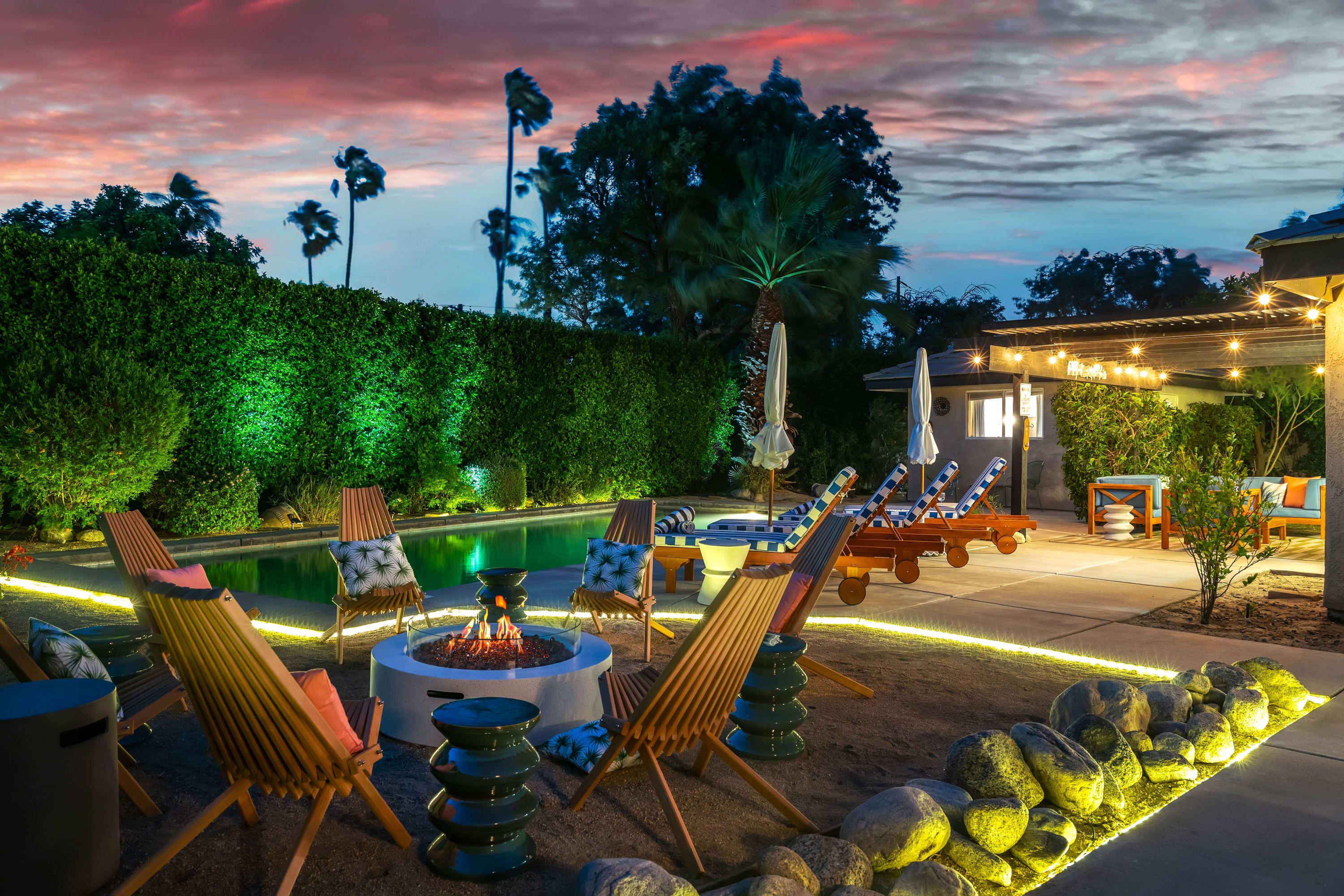 Un espace aménagé au bord de la piscine, avec des chaises longues, un foyer et une terrasse bien éclairée.
