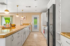 A modern kitchen with white cabinets, a granite countertop, and a black refrigerator.