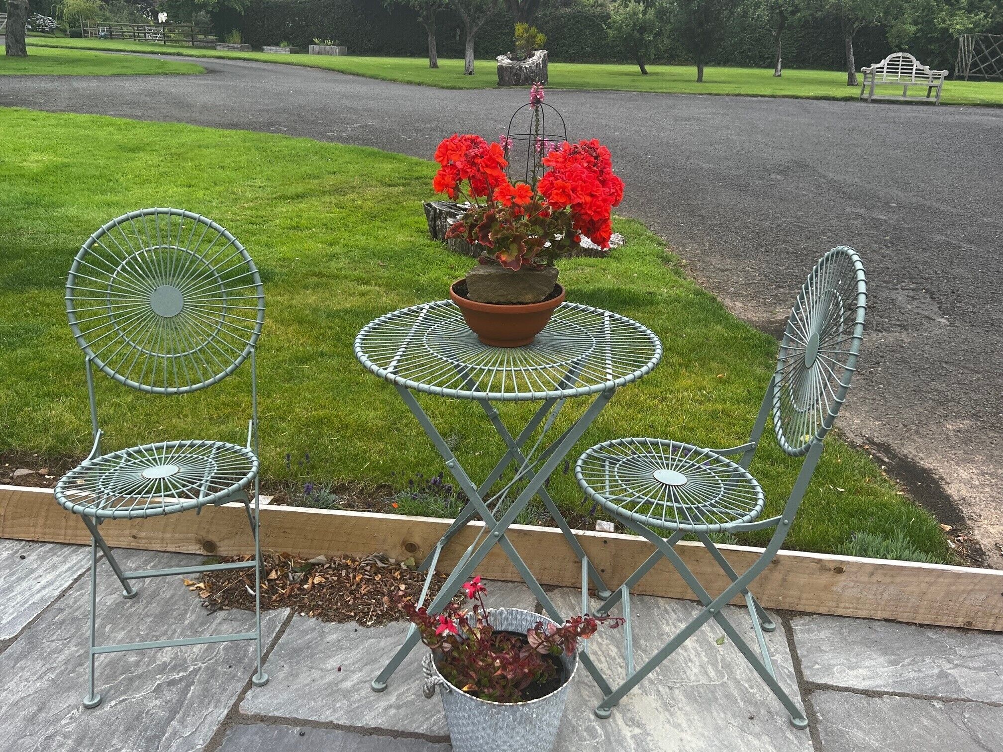 Une table en métal et quatre chaises, le tout installé dans un jardin.