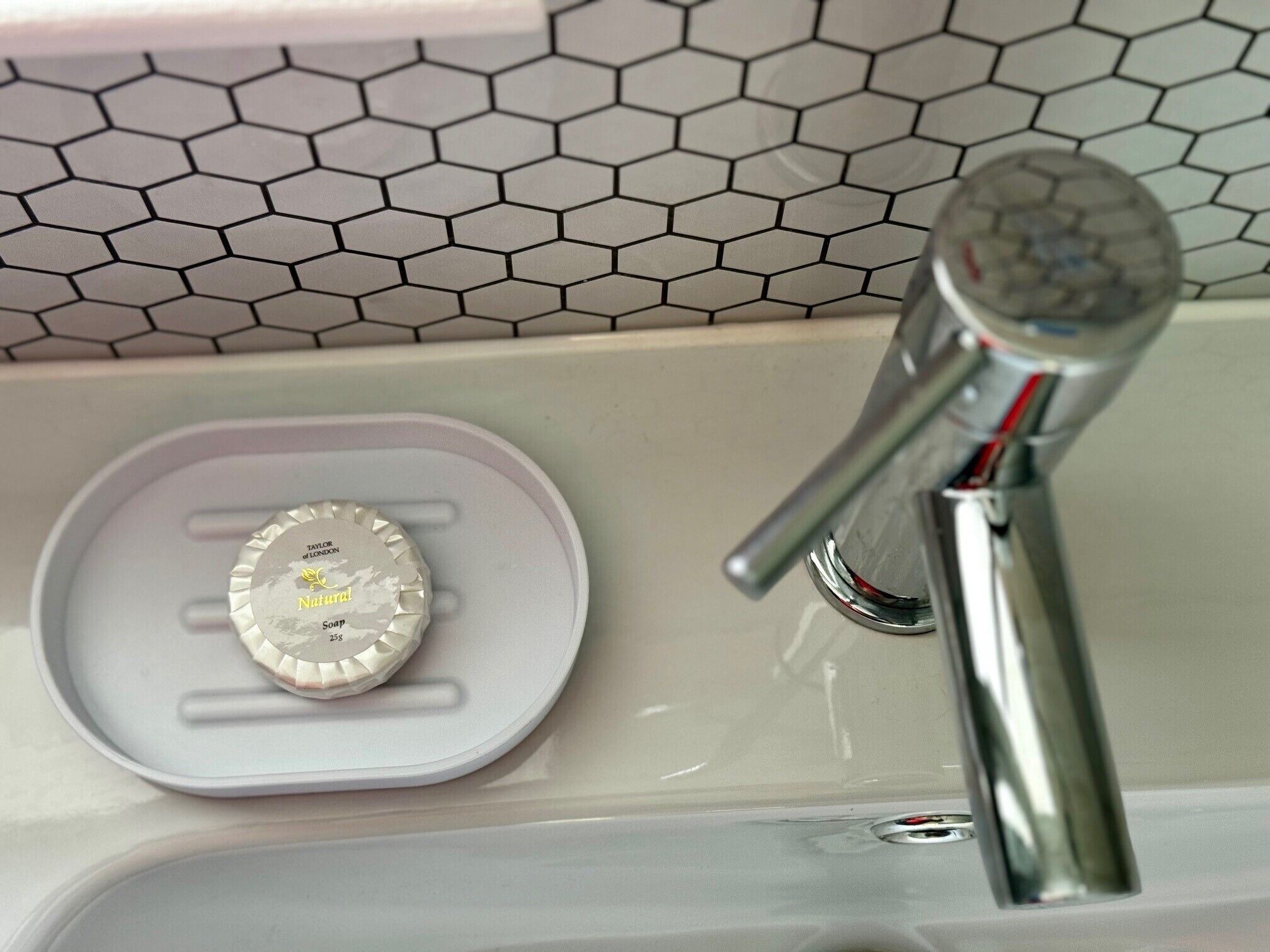 Een badkamer met een moderne kraan en zeepbakje.