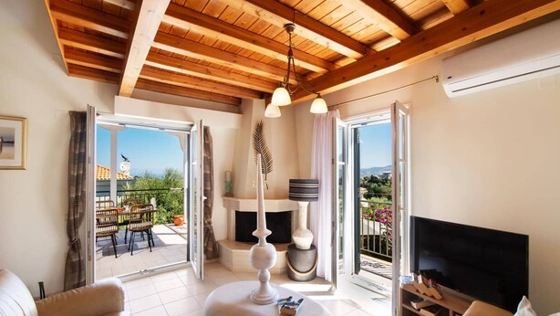 Un salon spacieux doté d’une cheminée, d’un téléviseur et d’un balcon aménagé avec du mobilier d’extérieur.