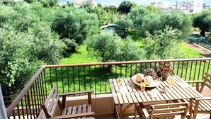 Ein Balkon mit Blick auf einen üppigen Garten und ferne Berge.