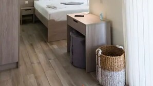 Een moderne hotelkamer met een bed, nachtkastje, lamp en een klein badgedeelte.