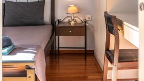 Ein Schlafzimmer mit Bett, Nachttisch mit Lampe, einem Sessel und einem Bild an der Wand.