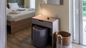A modern hotel room with a bed, bedside table, lamp, and a view of the outdoors through a sliding door. - Estia Coastal Dream - Lush Enchanting Garden Gem (Pylos-Nestoras)