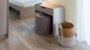 Una habitación de hotel con cama, mesita de noche, lámpara y un espejo en la pared.
