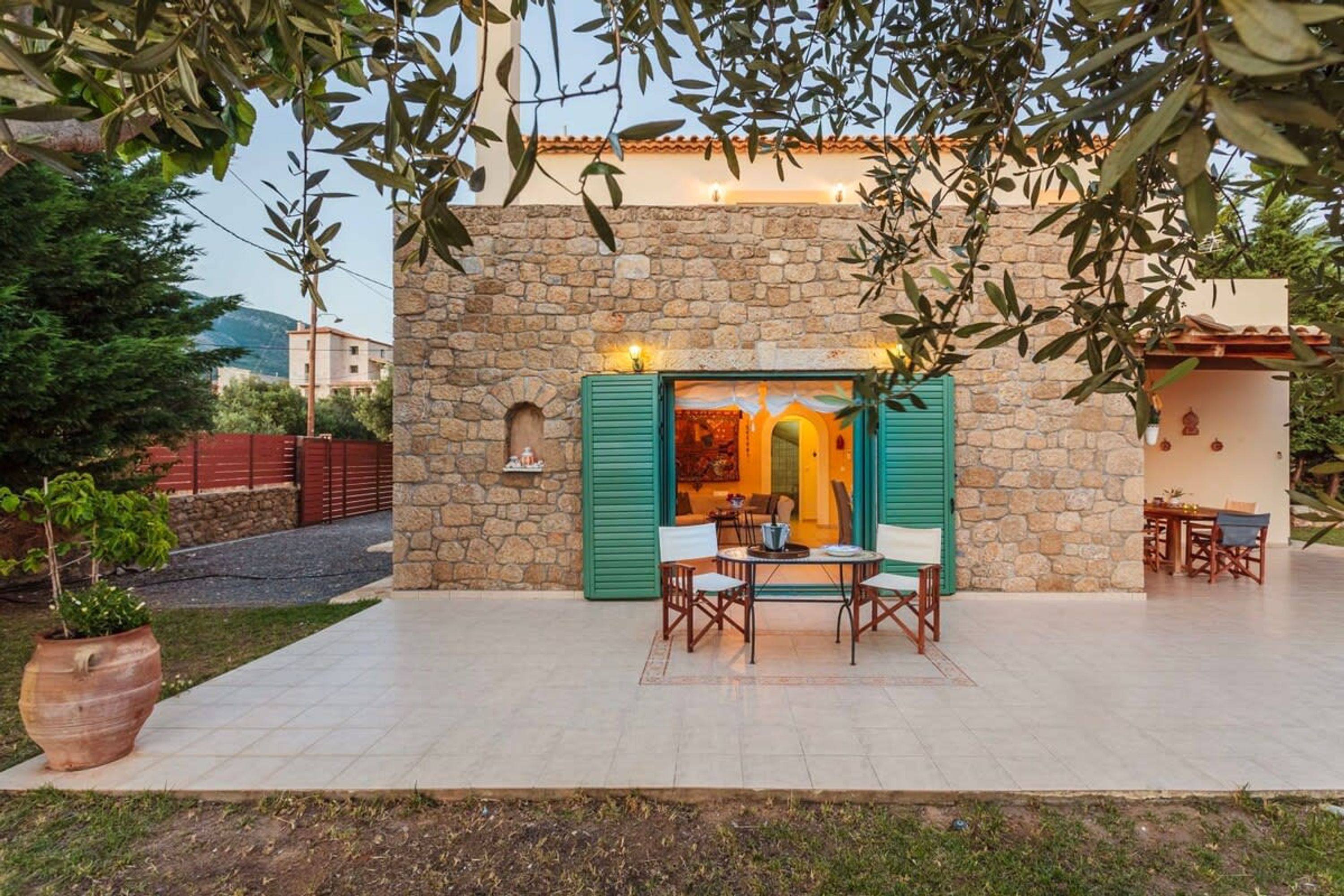Un edificio de piedra con un patio que cuenta con una mesa, sillas, una planta en maceta y vistas al interior.