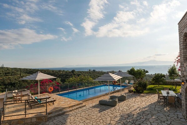 Un espace piscine équipé de chaises longues, de parasols et offrant une vue sur le paysage.