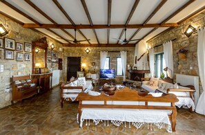 A rustic living room with stone walls, wooden furniture, and a stone floor. - Once Upon a Time - A Castle of Magical Sunsets (Kalamata)